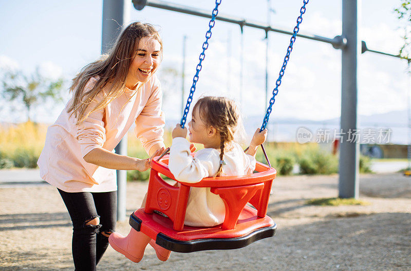 妈妈推着女儿在公园里荡秋千