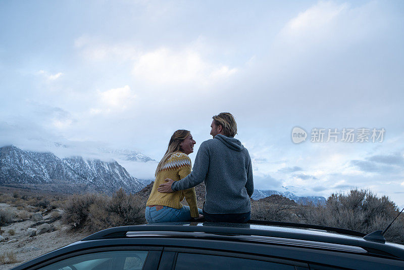 一对夫妇在车顶凝视着山景