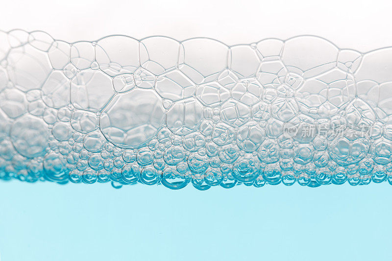 在清晰的蓝色液体背景下的肥皂泡泡的细节