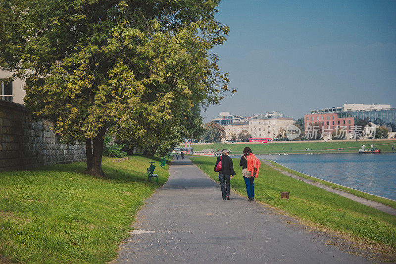 在一个阳光明媚的日子里，人们沿着克拉科夫的威斯拉河散步
