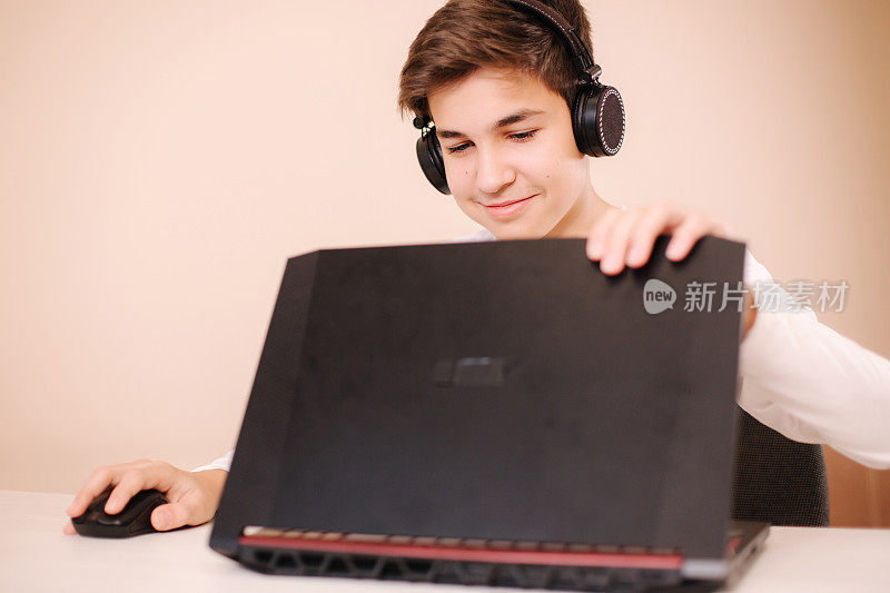 小男孩戴着无线耳机打开笔记本电脑，开始玩游戏。少年帅哥汽船