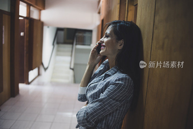 一位女商人在一幢办公楼的走廊里讲电话。