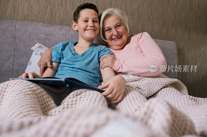 小男孩和他的奶奶正躺在床上，读睡前故事。