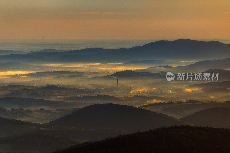 日出时暗金色的风景，中心有一个烟囱和许多山的线条