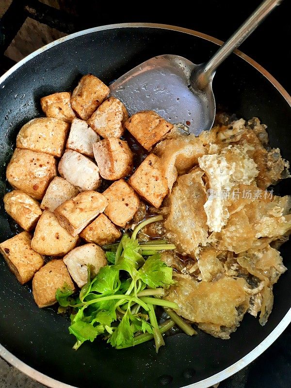 在平底锅中煸炒豆腐，准备食物。