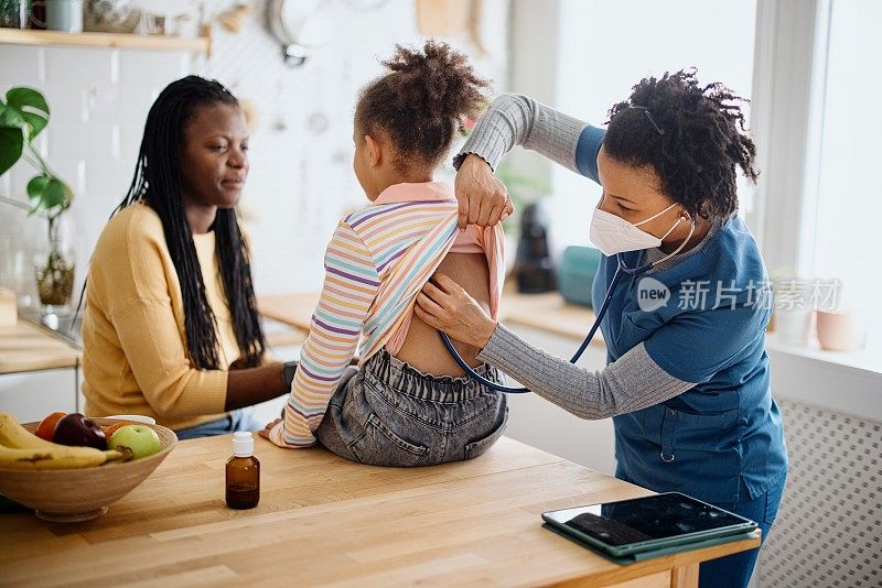 一位黑人女医生在一次家访医疗预约中，用听诊器检查儿科病人的肺部。