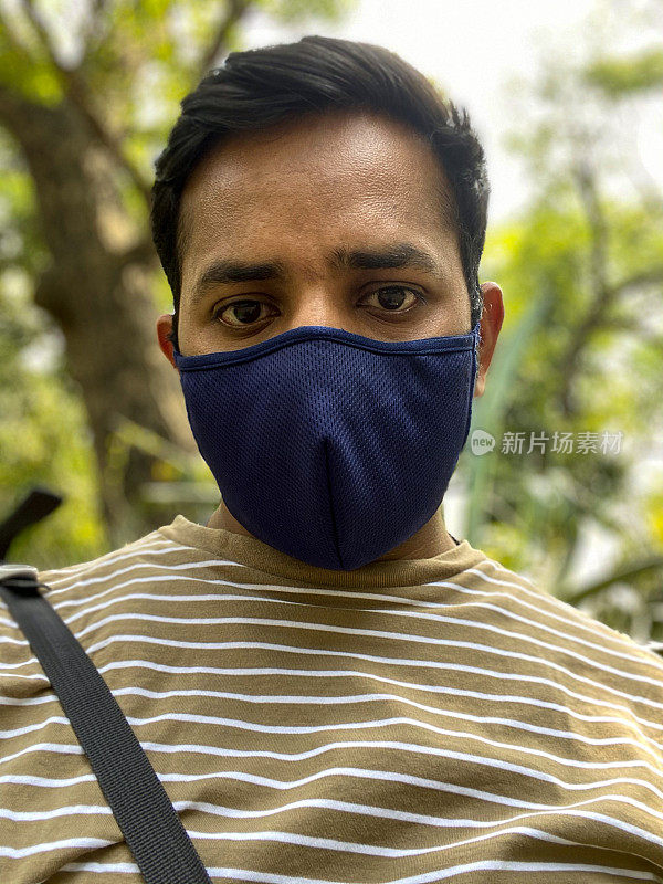 在全球突发卫生事件、隔离和疾病期间，印度男子在户外戴着医用口罩保护冠状病毒Covid-19病毒，戴着口罩
