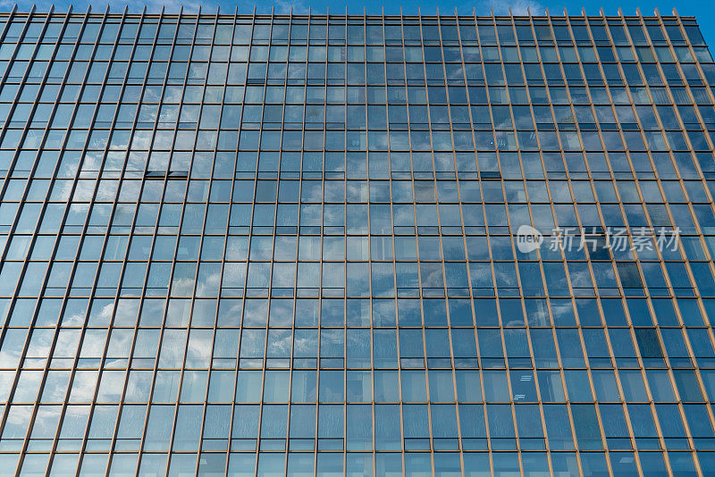现代建筑的特写。蓝天白云映照在玻璃外墙上