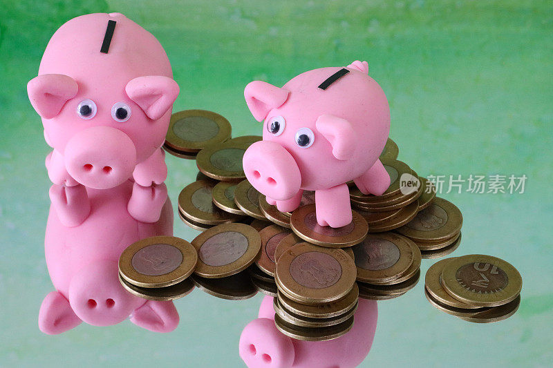 特写图像的猪储蓄罐与一堆硬币在镜子表面，升高的观点，关注前景，斑驳的绿色背景，家庭财务和储蓄的概念