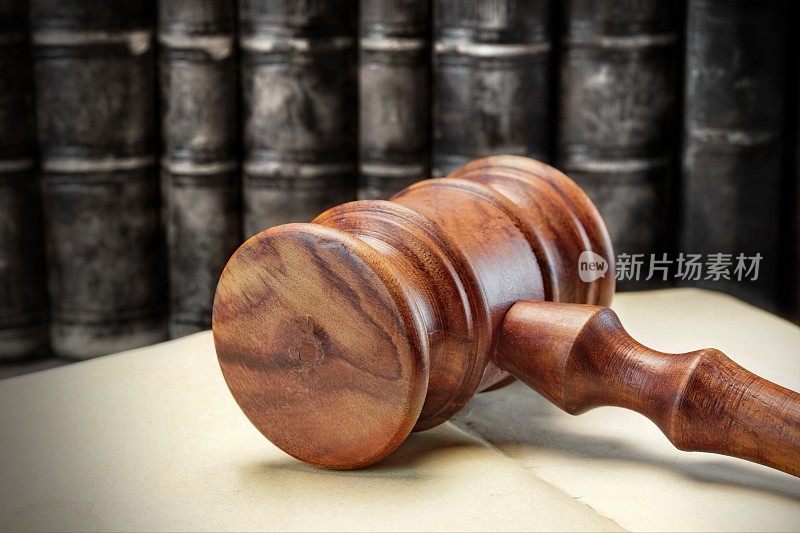 木制的法官或拍卖商的木槌和旧的法律书籍