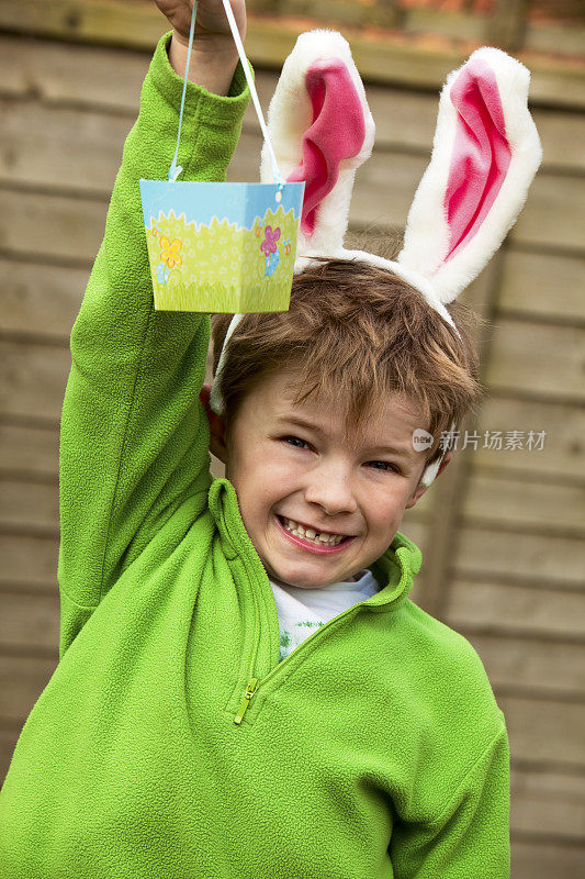 男孩戴着兔子耳朵，拿着篮子寻找复活节彩蛋