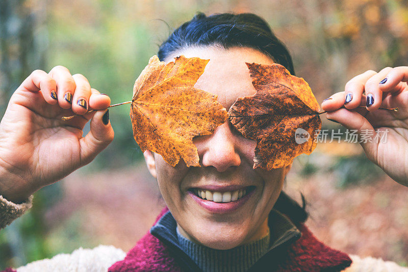 用树叶遮住脸的女人