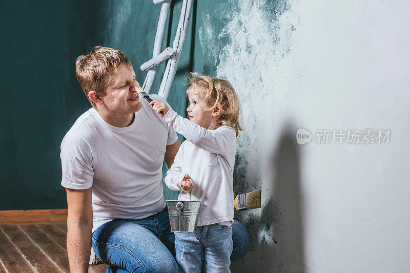 家庭，快乐的女儿和爸爸一起修房子，粉刷墙壁，