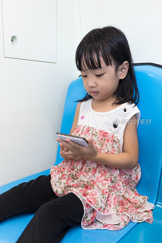 亚洲华人小女孩坐在捷运里拿着手机