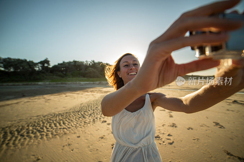 一名年轻女子在海滩上用可穿戴相机自拍