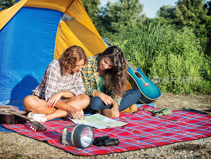 野营:朋友们在帐篷里看地图