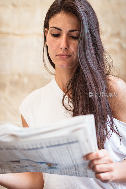 微笑的女人在城市里读报纸