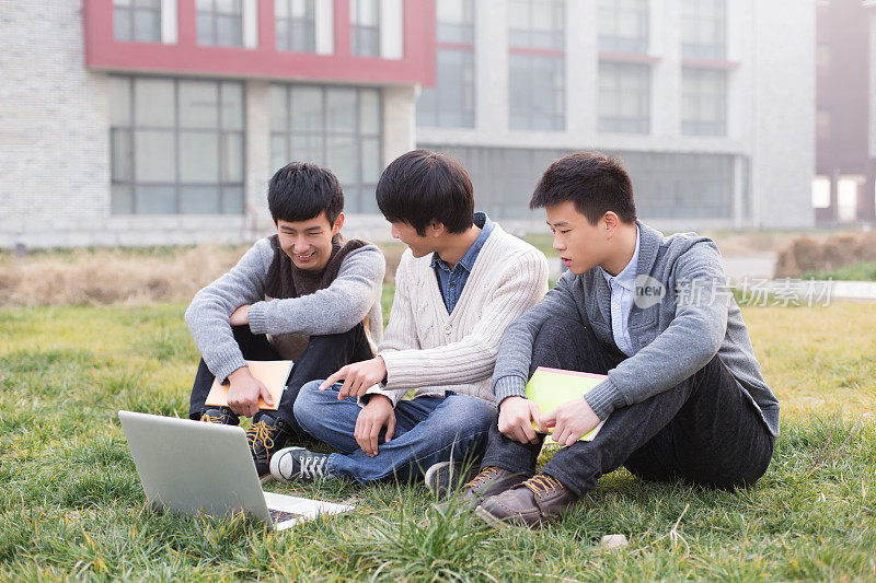 在校园里使用笔记本电脑的大学生