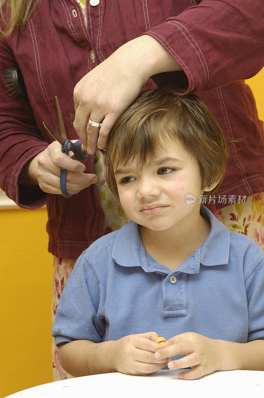 不高兴的男孩正在剪头发