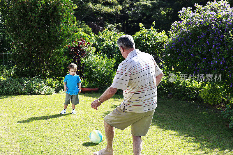 爷爷和孙子在花园里踢足球