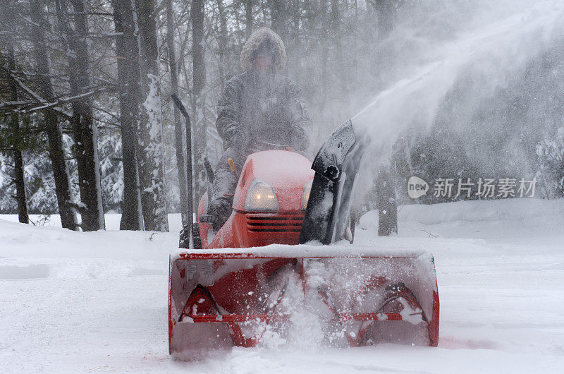 在大雪覆盖的地面上用吹雪机吹雪的人