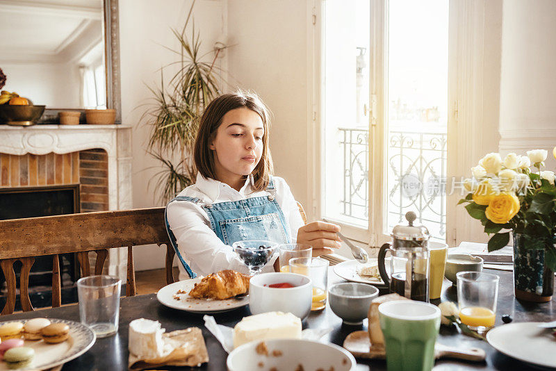 沉思的法国少女独自坐在早餐桌上