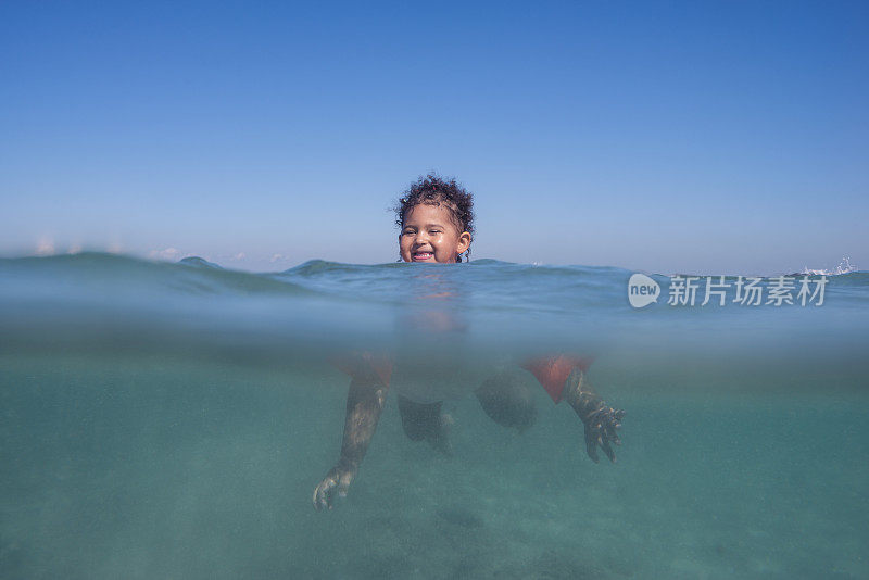 婴儿在碧水大海里学习游泳。