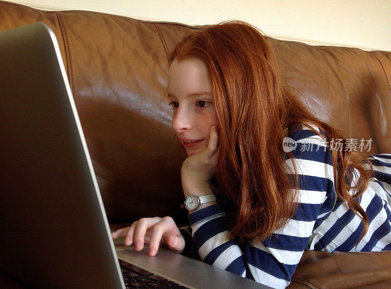 一个女孩在轻松的家庭环境中使用笔记本电脑