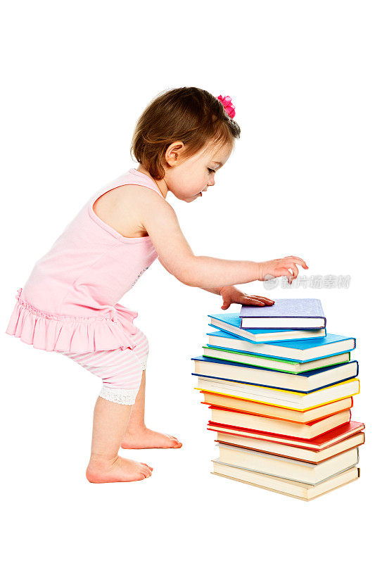 可爱的蹒跚学步的女孩，集中精力堆积书籍
