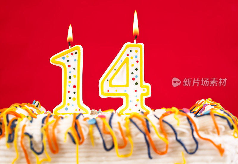 用14号燃烧的蜡烛装饰生日蛋糕。红色的背景。