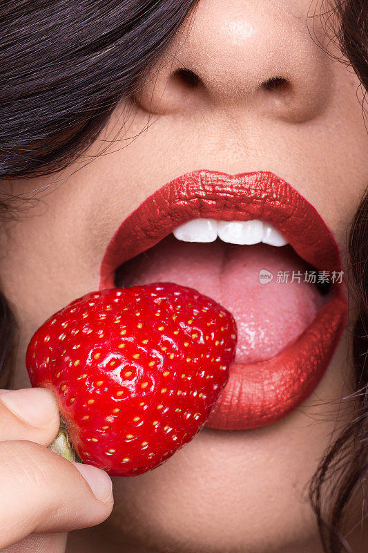 女人皮唇舌，舔着草莓，涂着红红的口红