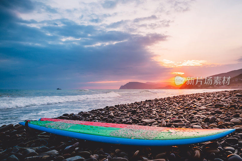 在日落或日出的颜色的石头海滩冲浪板。