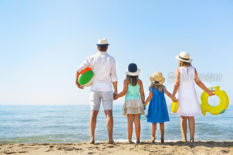 一个家庭和两个孩子在海滩上的肖像。假日及旅游概念