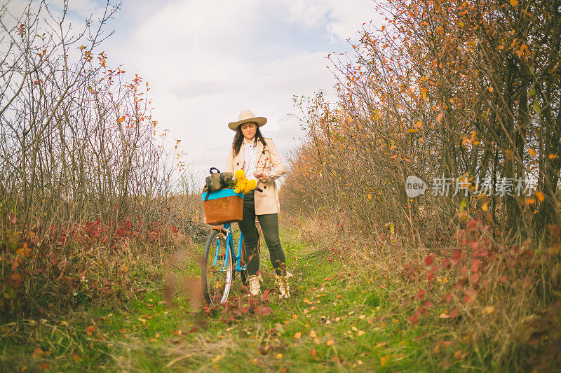 女孩骑着自行车穿过秋天的森林