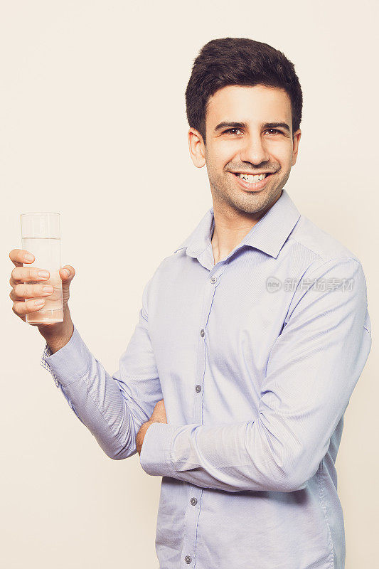 快乐的年轻英俊的男人拿着一杯水