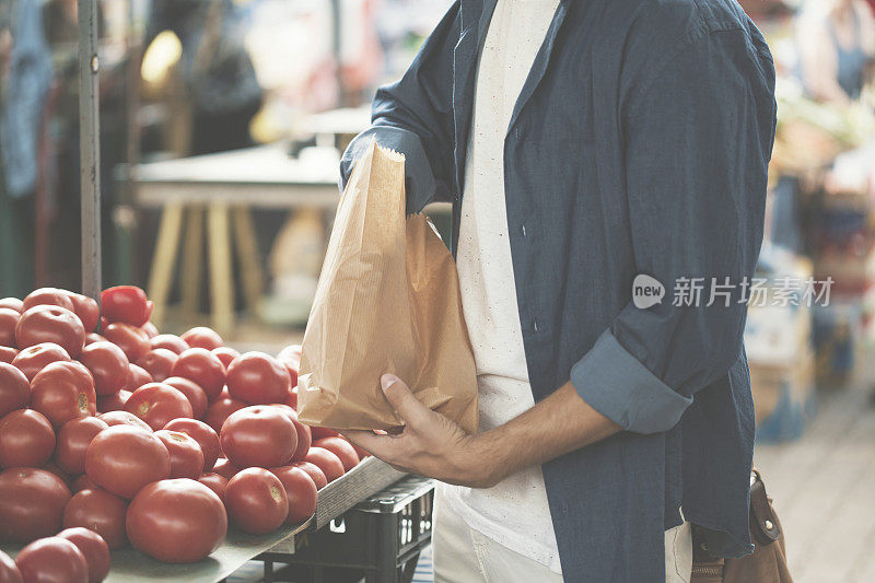 一个年轻人在市场上买西红柿
