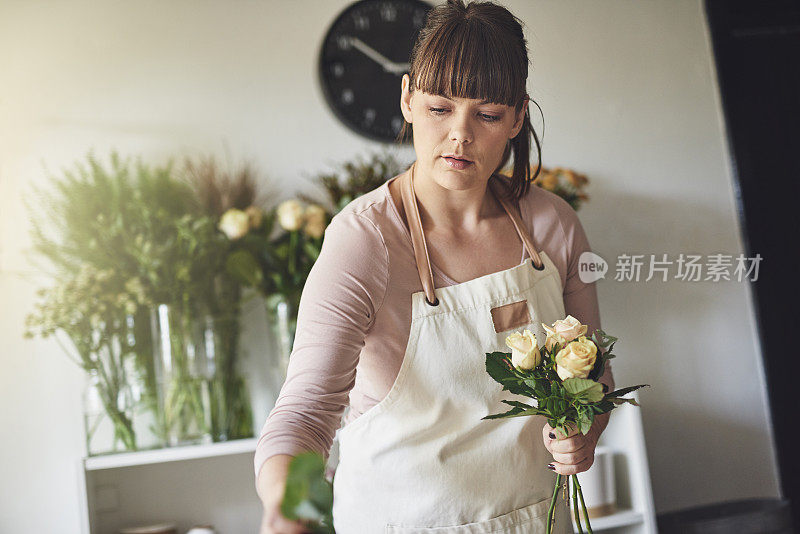 年轻的女花匠正在她的花店里做一束花