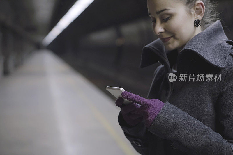 一个年轻女子在火车站用智能手机