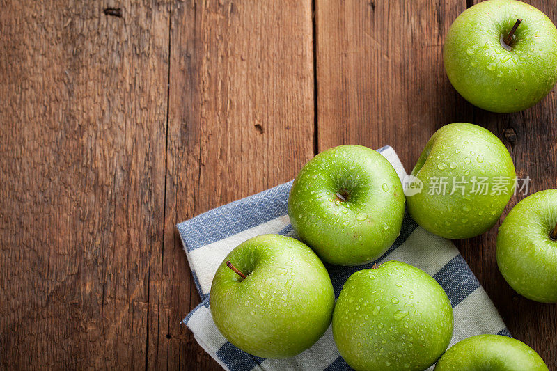 一个木碗里装着成熟的青苹果，放在一张旧的质朴的桌子上。木制背景上有用的水果。顶部视图与复制空间