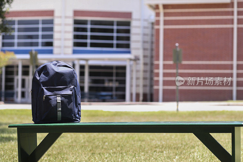 学生的背包放在学校前面的长凳上。