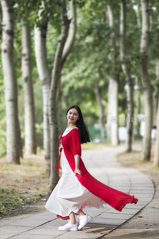 一个穿红衣服的女孩在公园散步