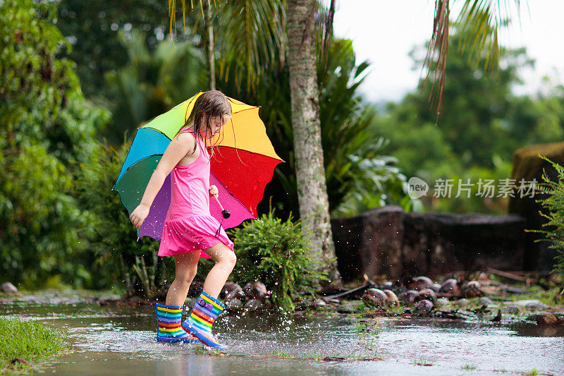 孩子们撑着伞在夏日的雨中玩耍。