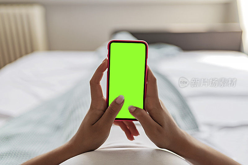 女性手握智能手机与色度键绿色屏幕
