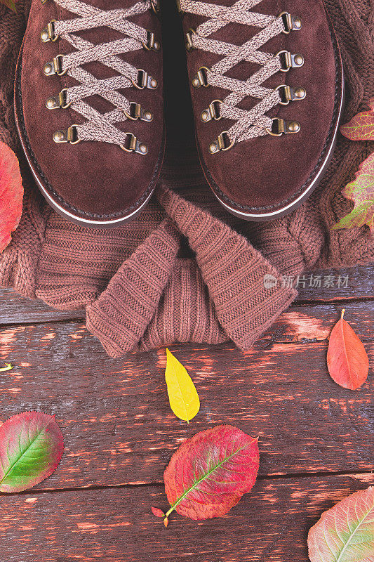 棕色人绒面革靴子与木制背景毛衣