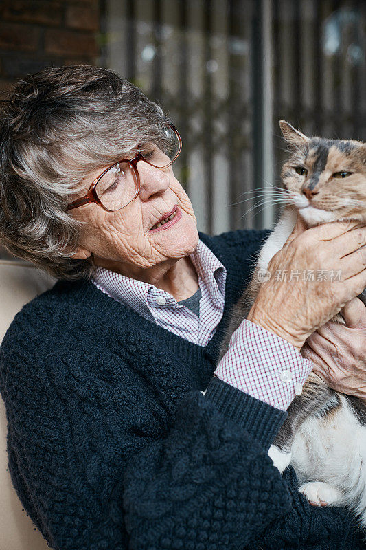 一位年长的女士在和她的宠物猫说话