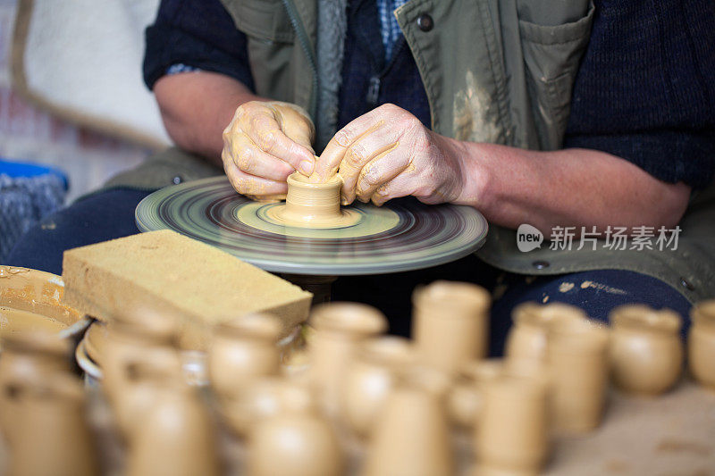 陶工的双手在陶工转盘上形成一个小花瓶