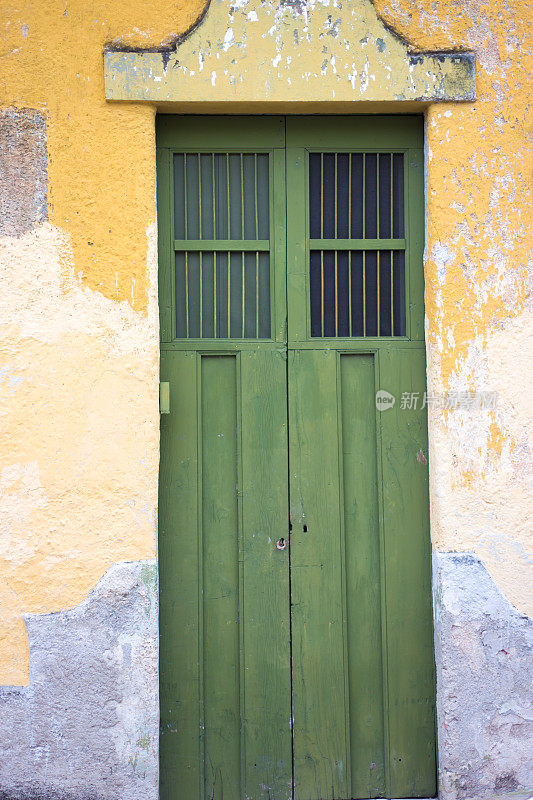 墨西哥尤卡坦:绿色木门在斑驳的黄色墙