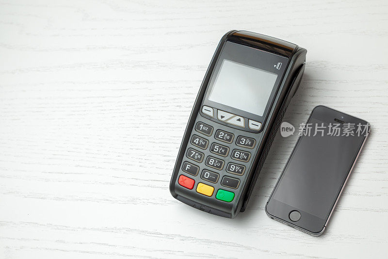 POS机，白色背景下的手机支付机。采用NFC技术的非接触式支付。