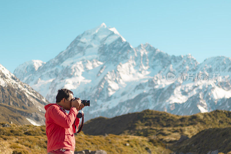 新西兰库克山;一个徒步旅行者在库克山的一条徒步小径上的阳光下拍照。