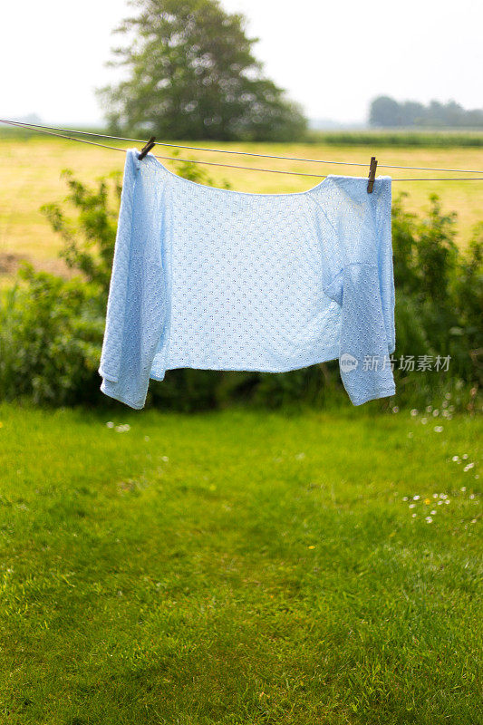 农村场景:女人在洗衣线上的淡蓝色毛衣
